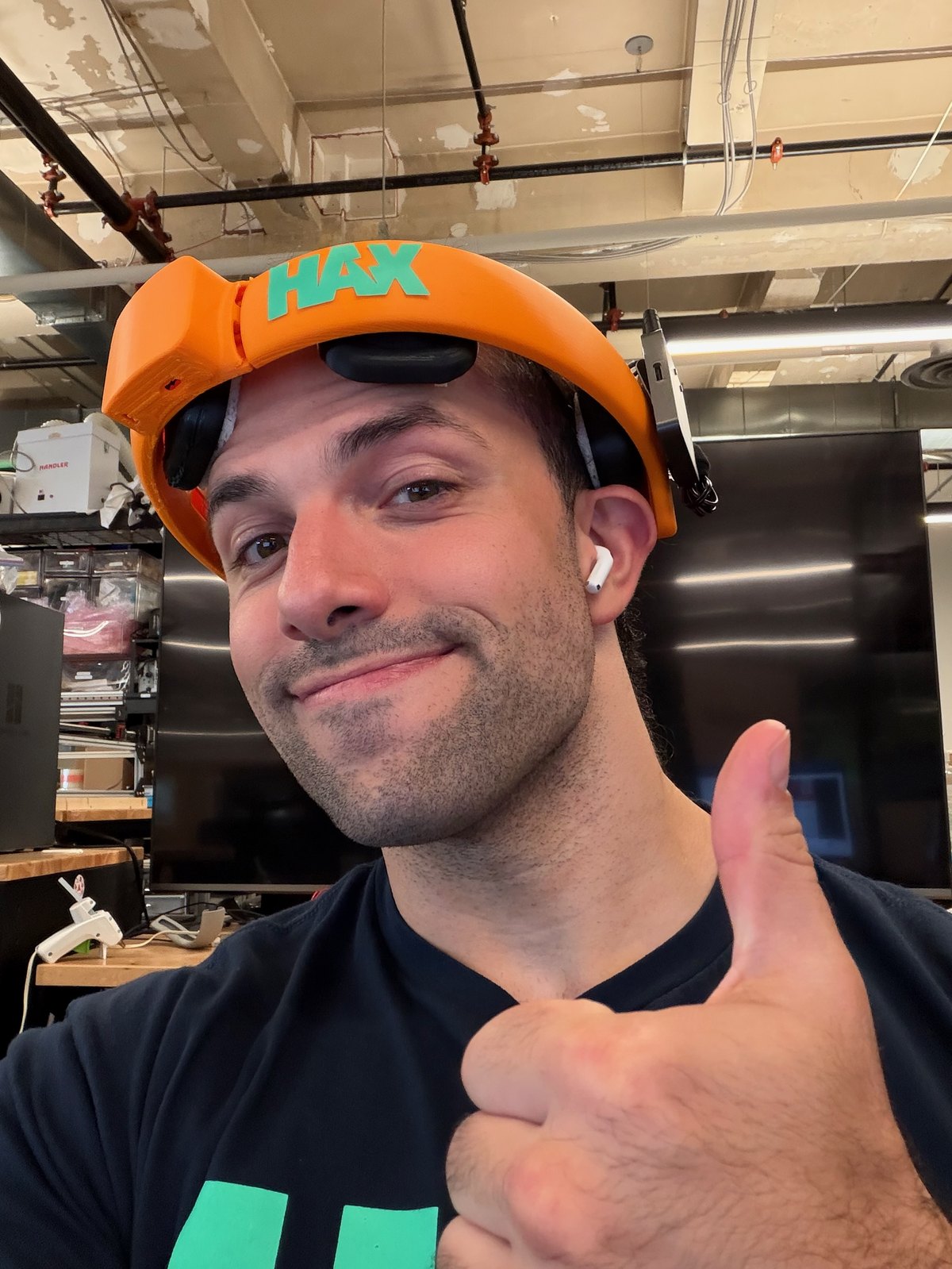 A General Neuroscience team member wearing the orange HAX-branded tES headset in the lab