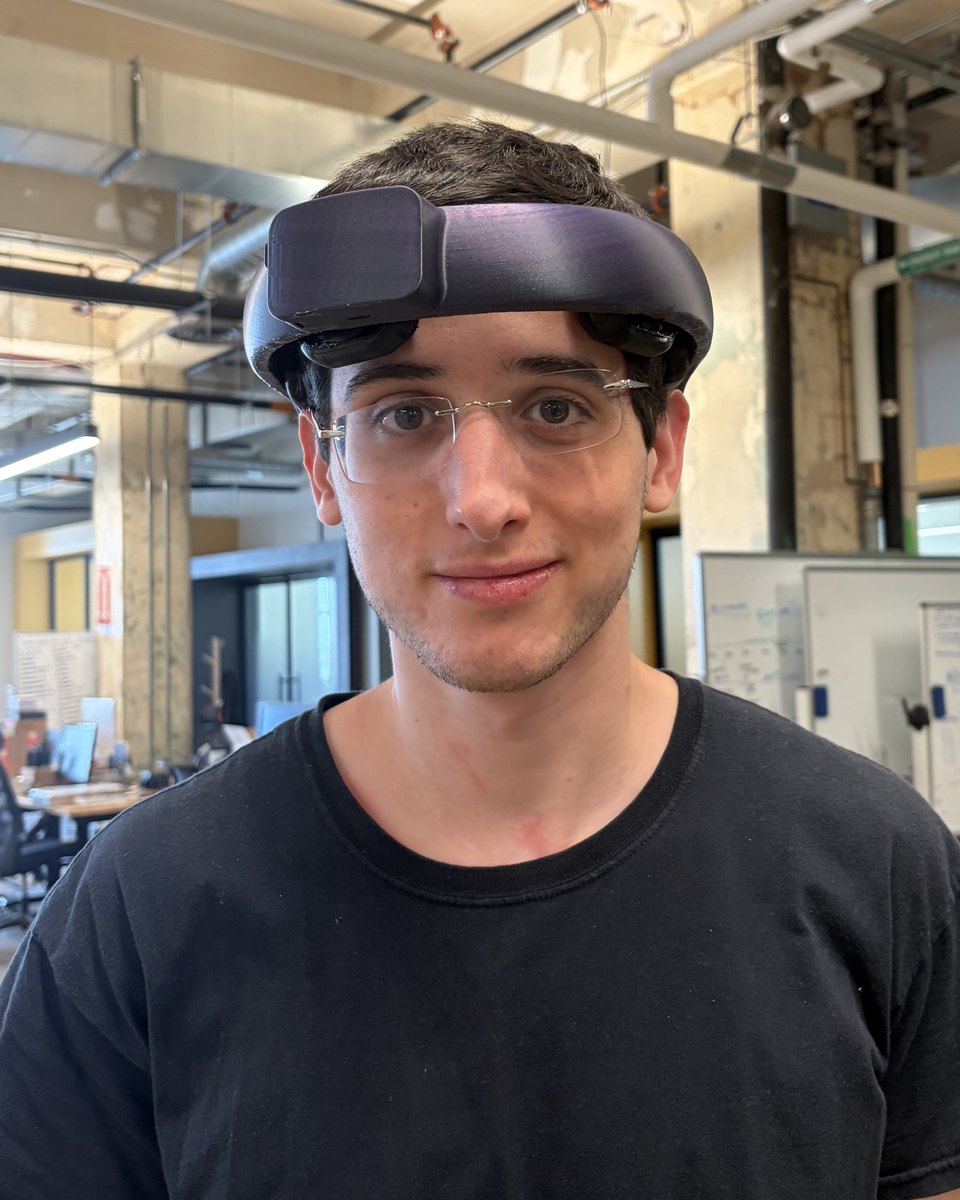 A team member wearing the v5 NeuroLingo headset: a slim dark band sitting above the brow, with the electrode pods visible at the temples