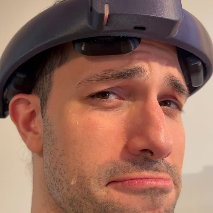 Luke wearing the headset with saline running down his cheek, looking miserable