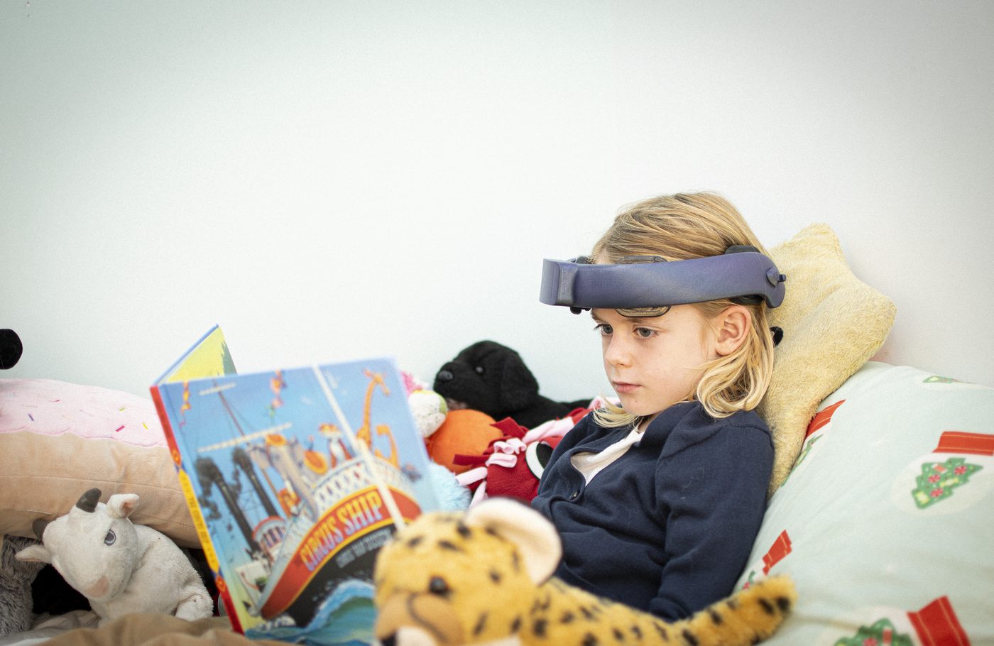 A child wearing the NeuroLingo headband reads a picture book