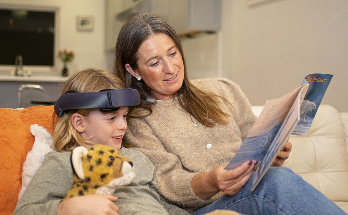 A child wearing the NeuroLingo headband reads with a parent on the couch