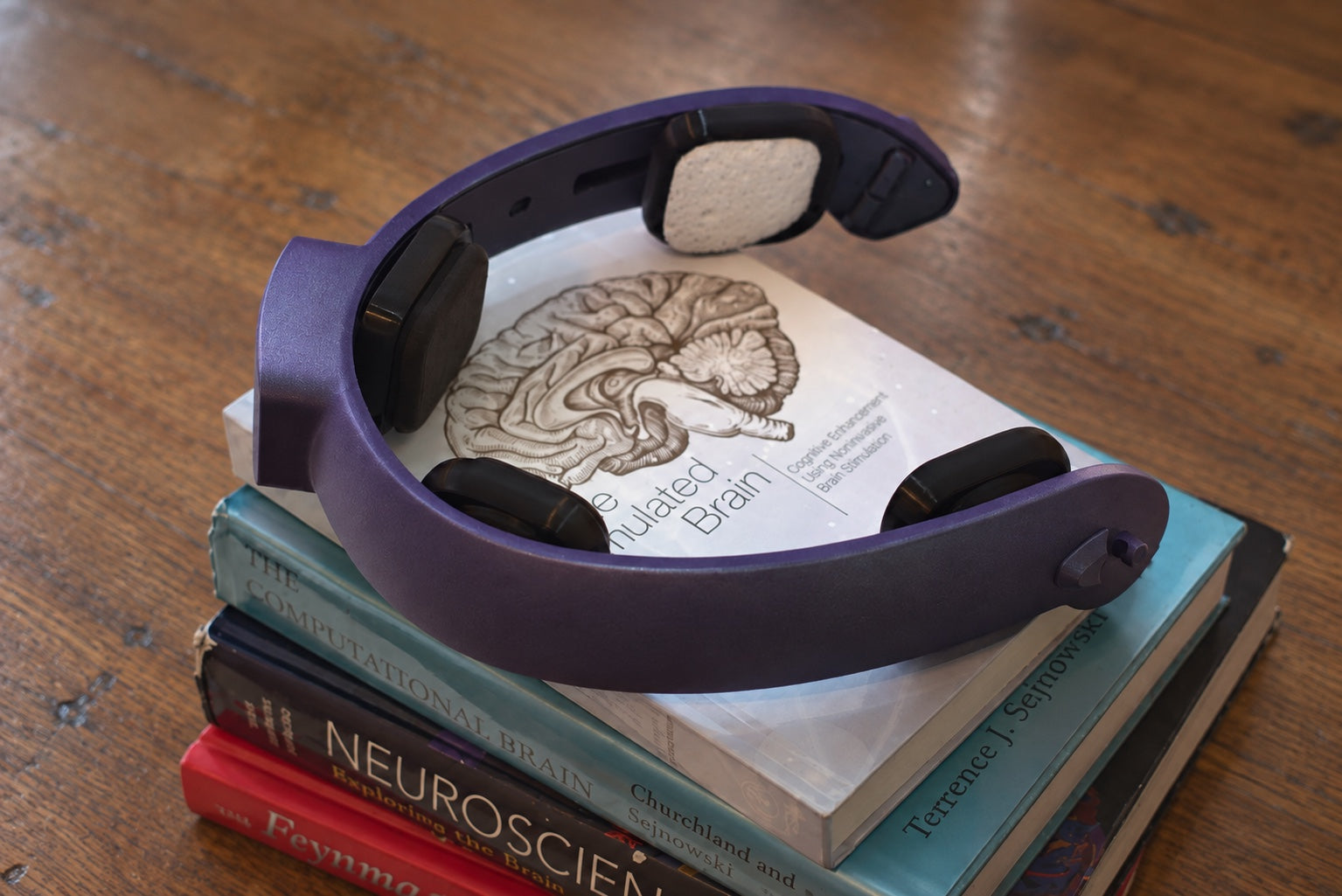 The NeuroLingo headband resting on a stack of neuroscience books